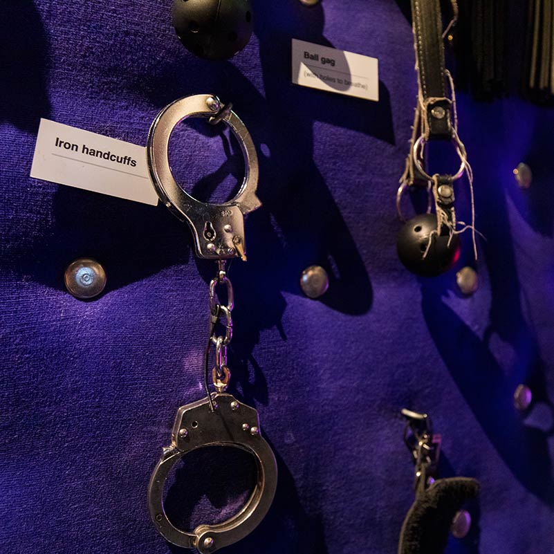 Handcuffs attached to a purple wall in the Red Light Secrets Museum.